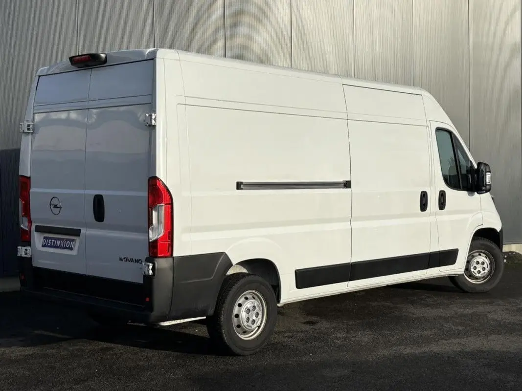 Vue 3/4 arrière droite d’un Opel Movano Fourgon blanc 2023 avec portes arrière battantes et protections noires.