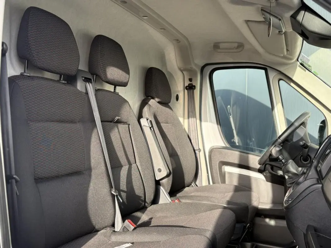 Vue intérieure côté droit montrant les trois sièges avant en tissu gris foncé du fourgon Opel Movano blanc.