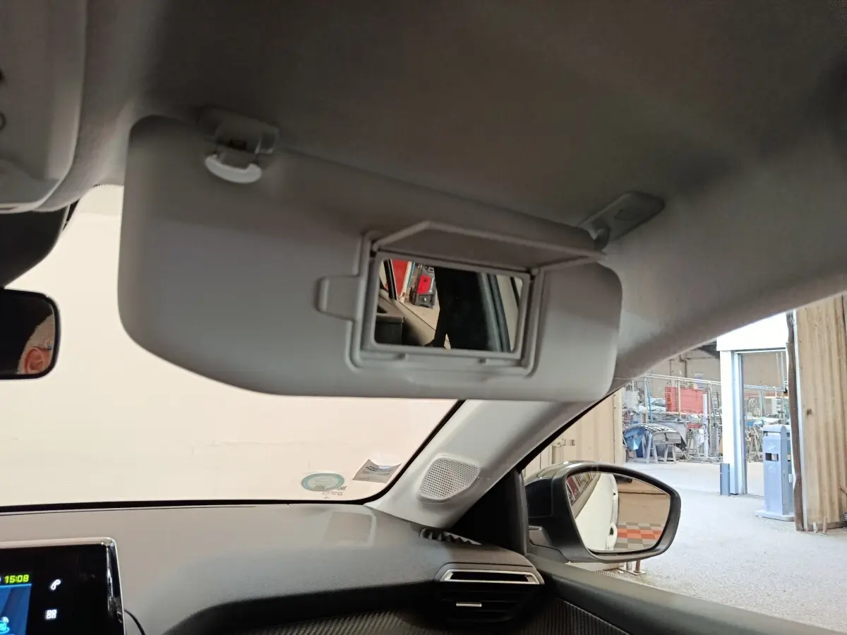 Intérieur du Peugeot 208 électrique blanc, vue sur pare-soleil avec miroir et rétroviseur côté droit.