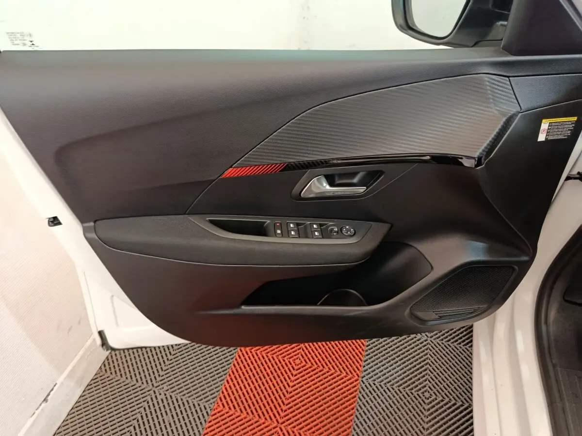 Vue intérieure de la porte avant gauche blanche du Peugeot 208 électrique avec insert décoratif noir et rouge.