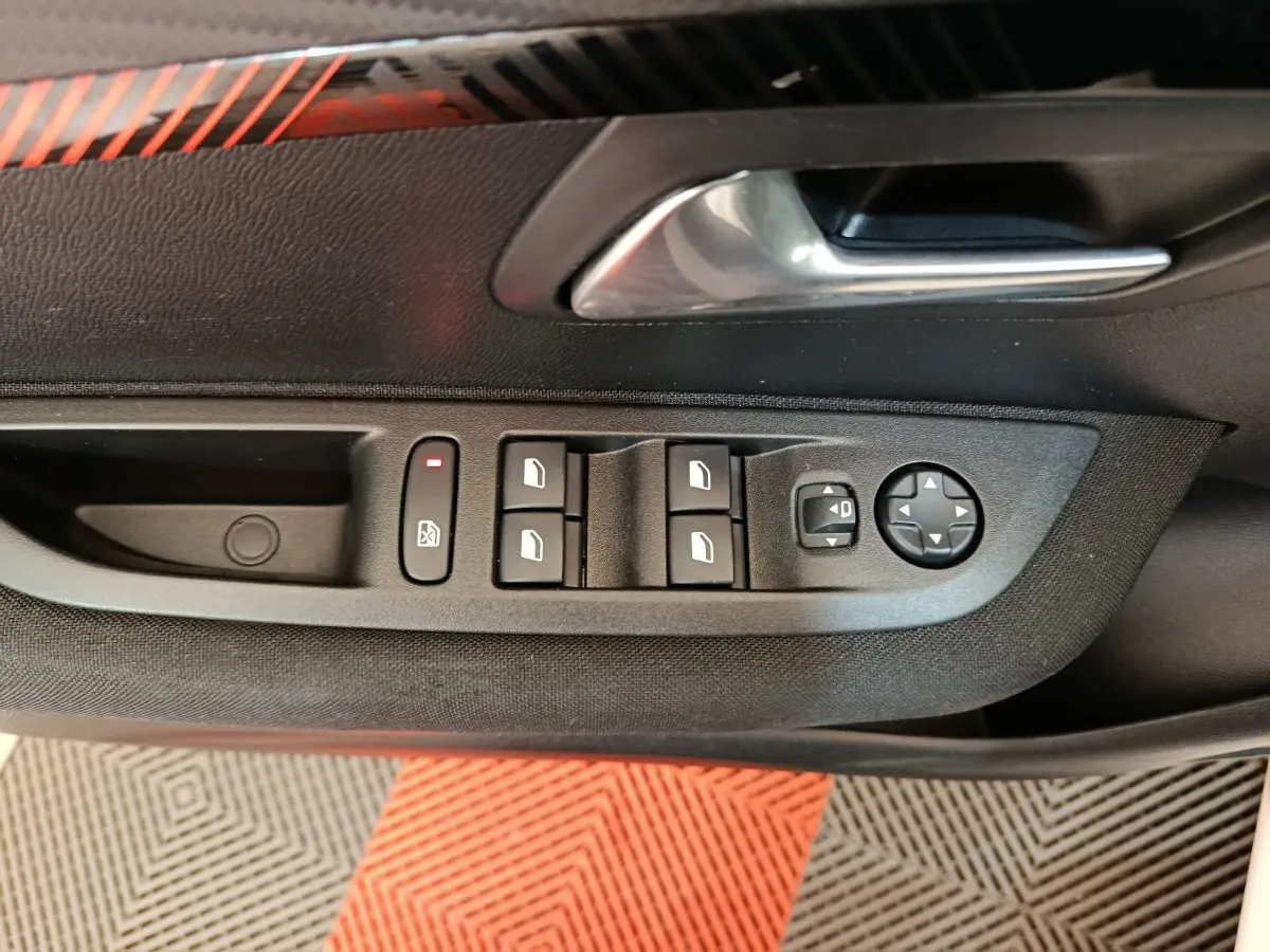 Commande des vitres électriques et réglage des rétroviseurs sur la porte côté conducteur d'une Peugeot 208 blanche électrique.