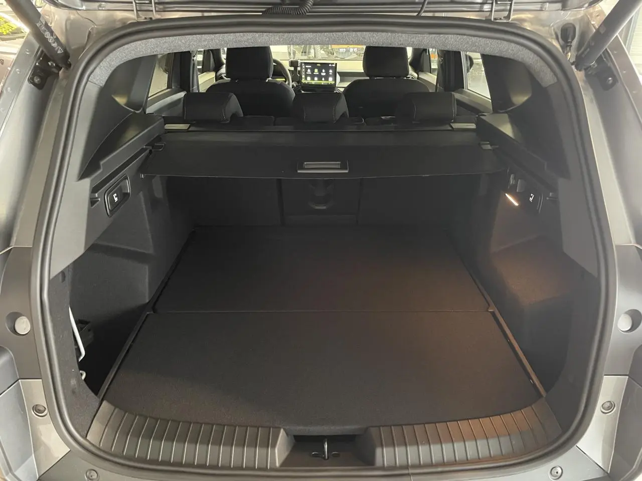 Coffre ouvert vu de l'arrière du Dacia Bigster gris schiste, montrant l'espace de chargement et la banquette arrière.
