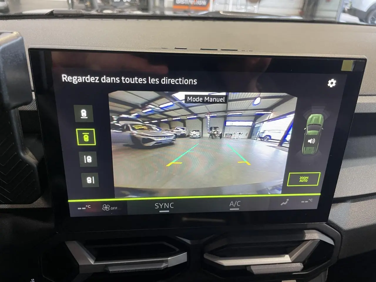 Écran tactile intérieur affichant la caméra multivues du Dacia Bigster gris schiste en mode manuel dans un garage.