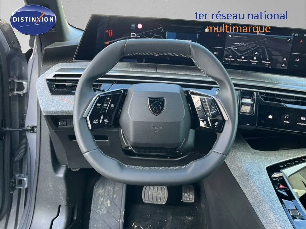 Vue centrée sur le volant cuir gris du Peugeot 5008 Hybrid 2025 avec tableau de bord numérique et écran tactile.