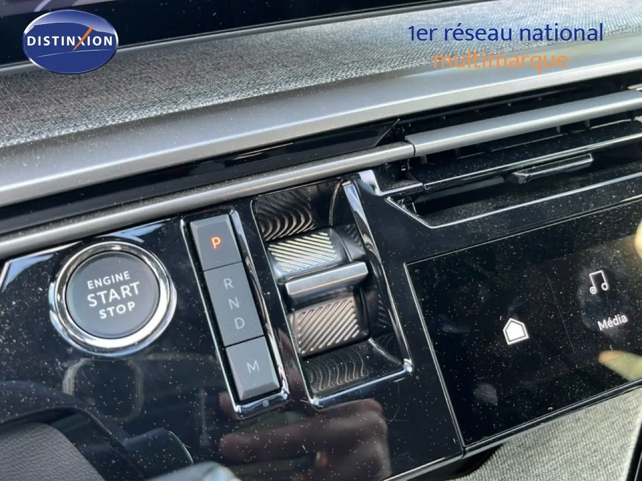 Gros plan sur la console centrale noire brillante du Peugeot 5008 gris, avec bouton start/stop et commandes de boîte automatique.