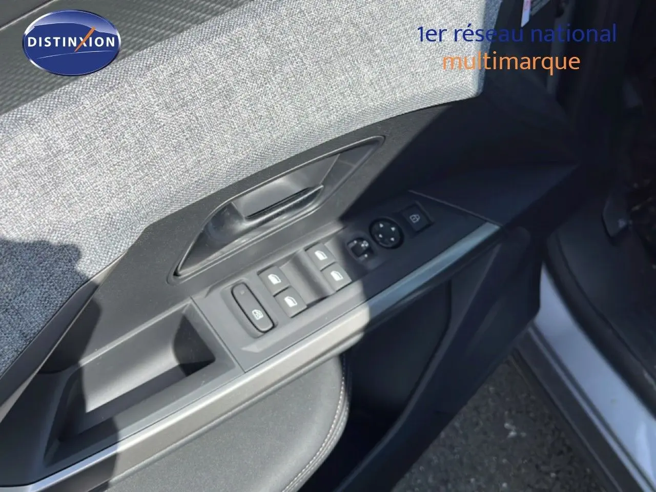 Gros plan sur la porte avant gauche du Peugeot 5008 gris Artense, montrant les commandes des vitres et rétroviseurs.