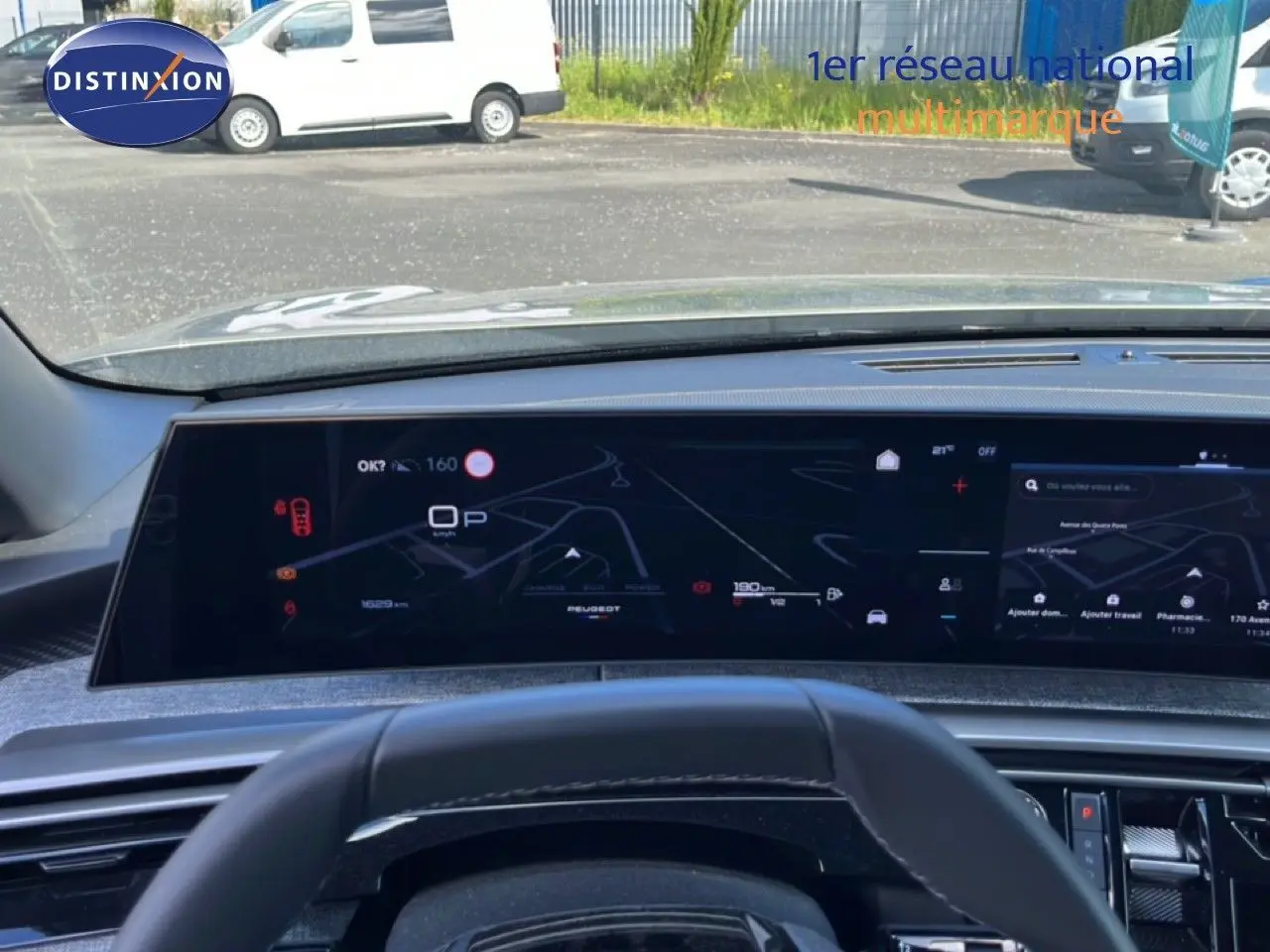 Vue intérieure centrée sur le tableau de bord numérique du Peugeot 5008 gris Artense, affichant la navigation et les informations de conduite.