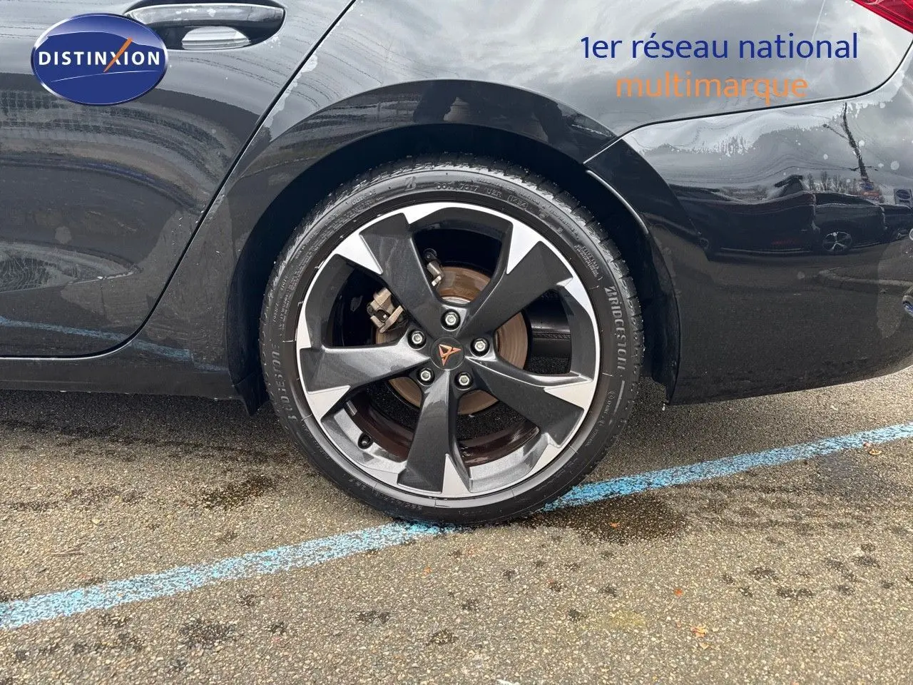 Gros plan sur la roue arrière droite d'une CUPRA LEON ST noire Midnight Metal avec jante bi-ton distinctive.
