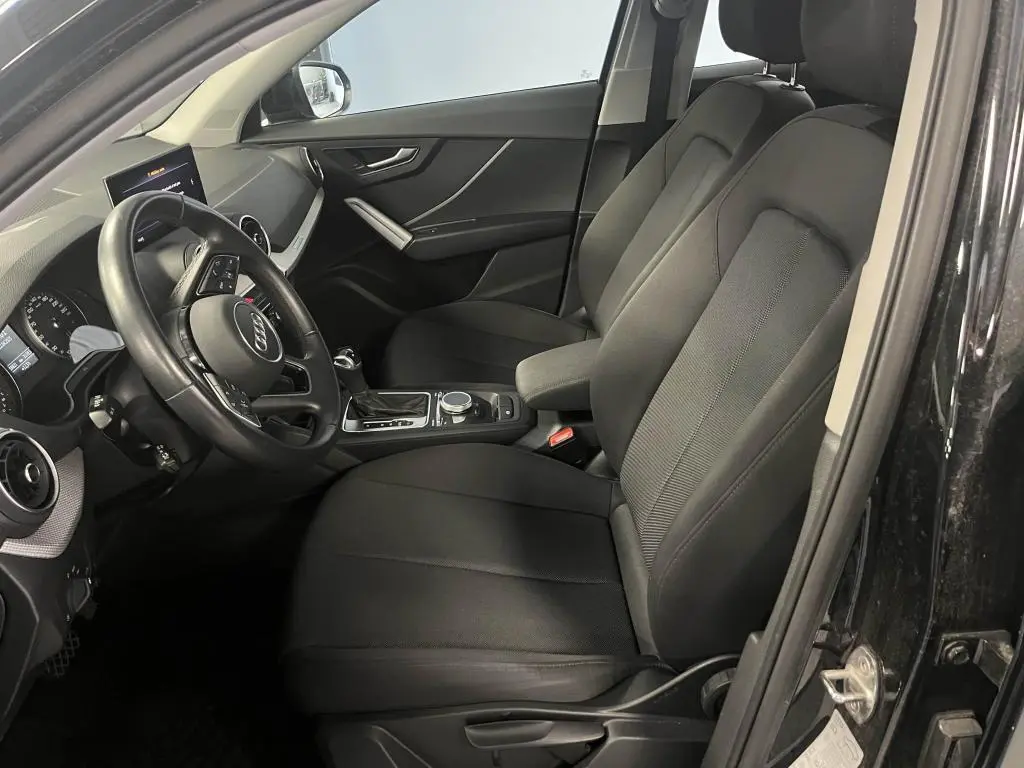 Intérieur noir de l'Audi Q2 2022 vu côté conducteur, avec volant cuir multifonction et console centrale moderne.