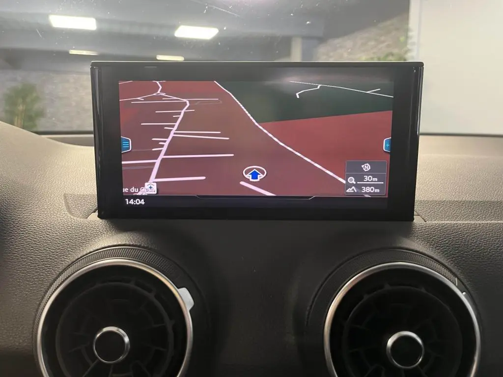 Écran central du système de navigation de l'Audi Q2 2022 avec ventilation circulaire noire et argentée visible en bas.