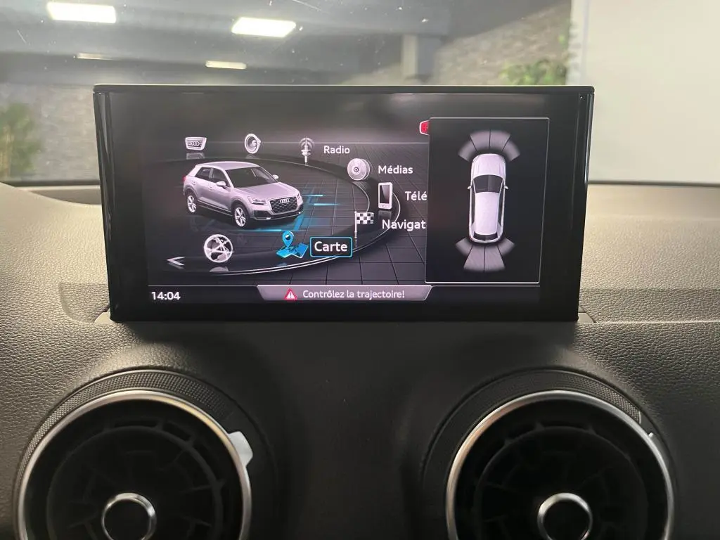 Écran central affichant la navigation et la vue 3D d'un Audi Q2 gris, avec alertes de trajectoire active.