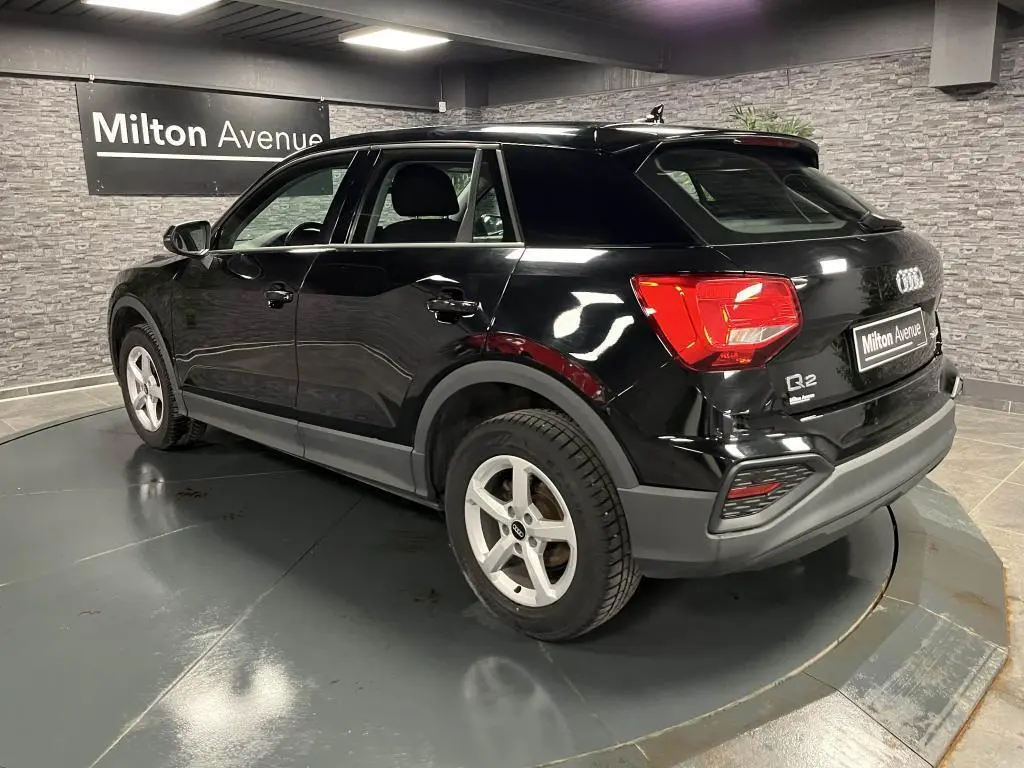 Audi Q2 noir brillant vue 3/4 arrière droit, avec jantes aluminium 5 branches et feux arrière LED visibles.