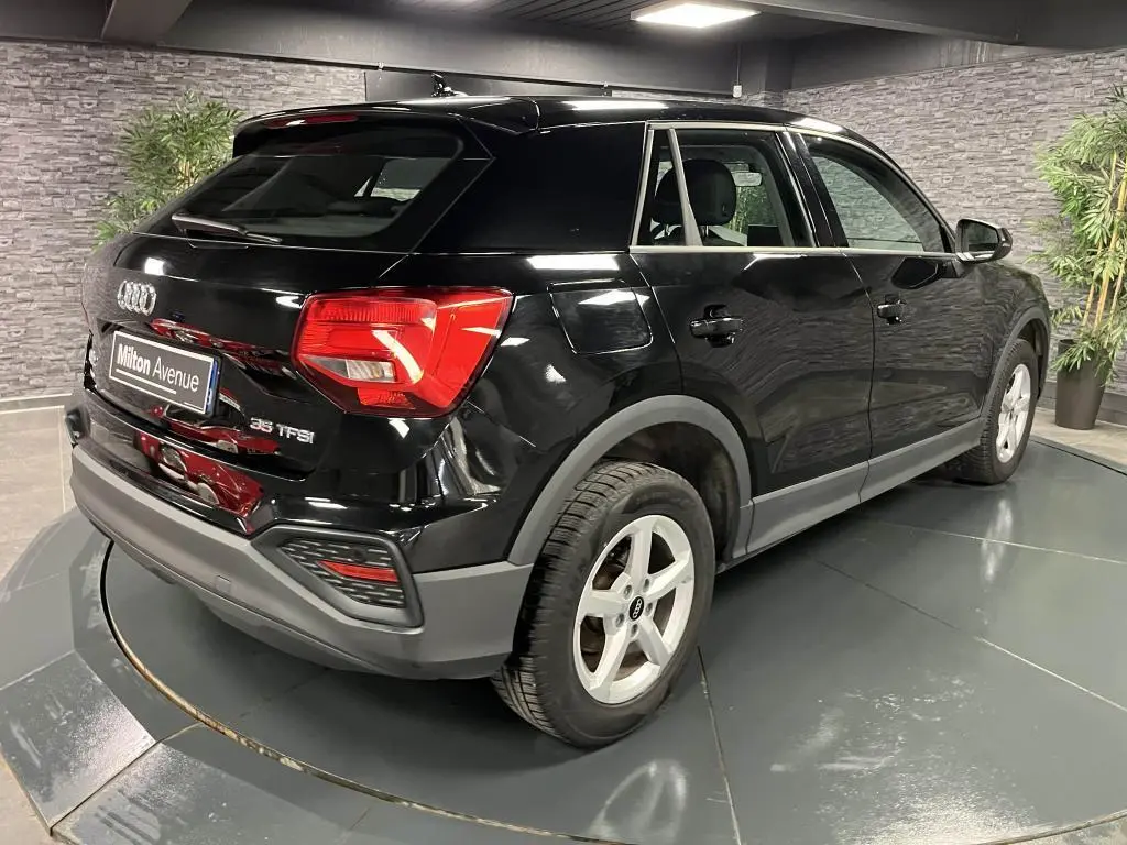 Audi Q2 noir brillant vue 3/4 arrière droit, avec jantes aluminium 5 branches et feux arrière LED rouges.