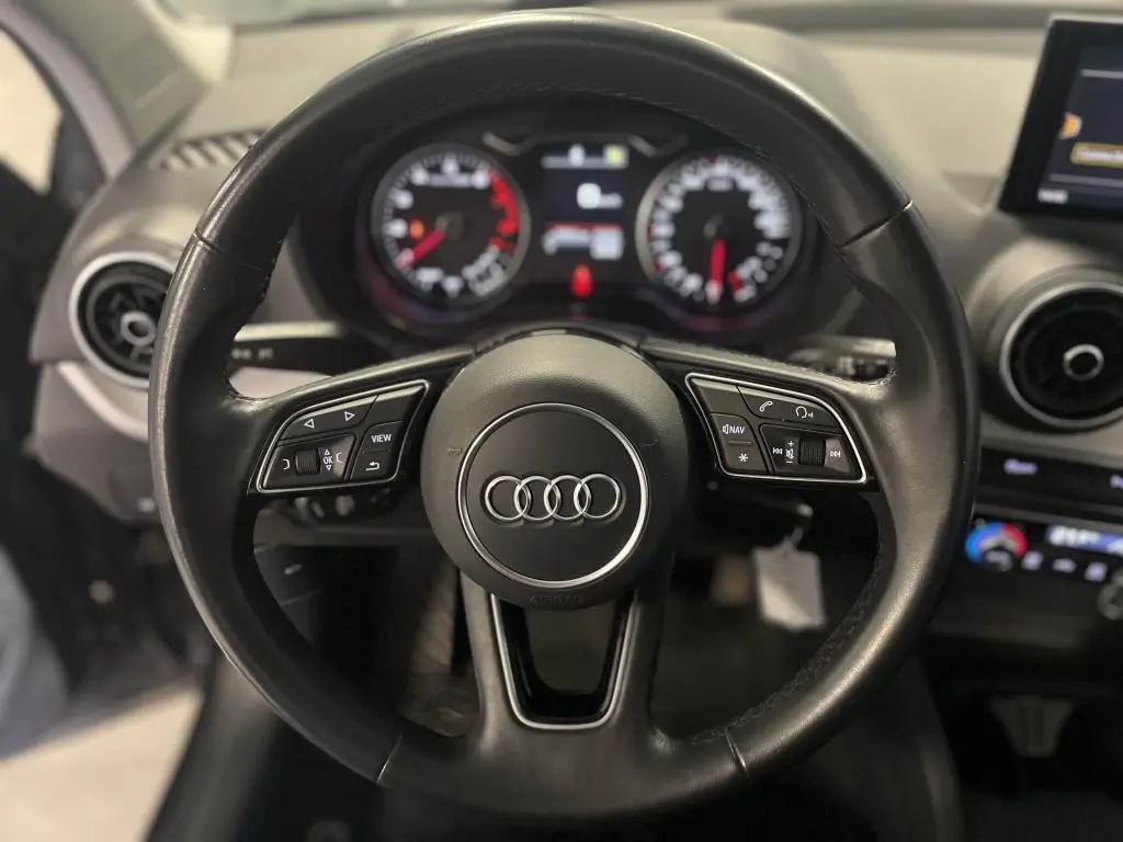 Volant en cuir noir multifonction d'Audi Q2 2022 avec tableau de bord et commandes visibles en arrière-plan.