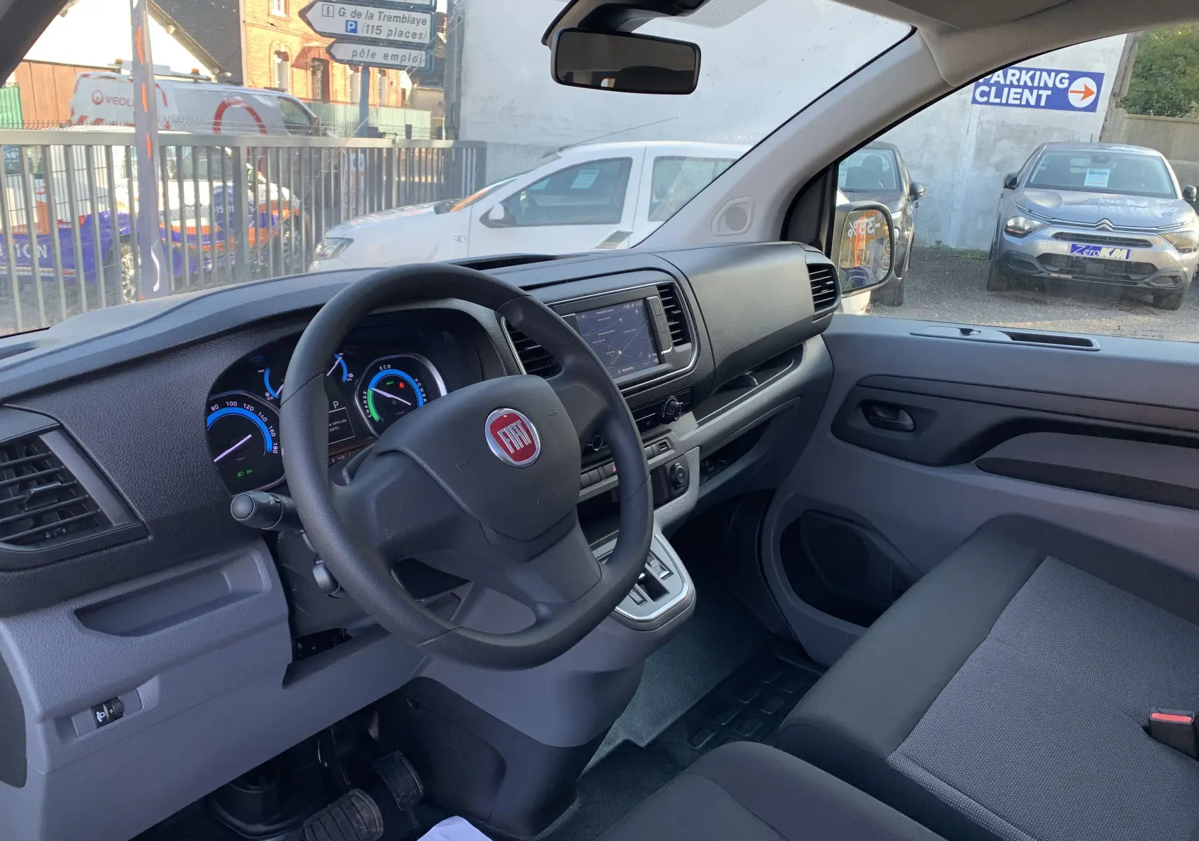 Intérieur du Fiat Scudo Combi électrique 2022 vu côté conducteur, tableau de bord moderne avec écran tactile et volant noir.