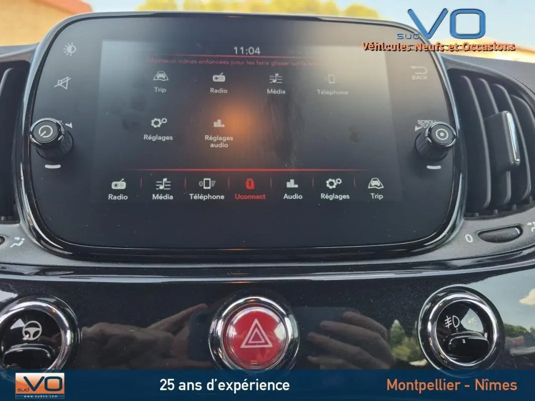 Écran tactile central de la console d'une FIAT 500C noire 2024, affichant les options multimédia et réglages.