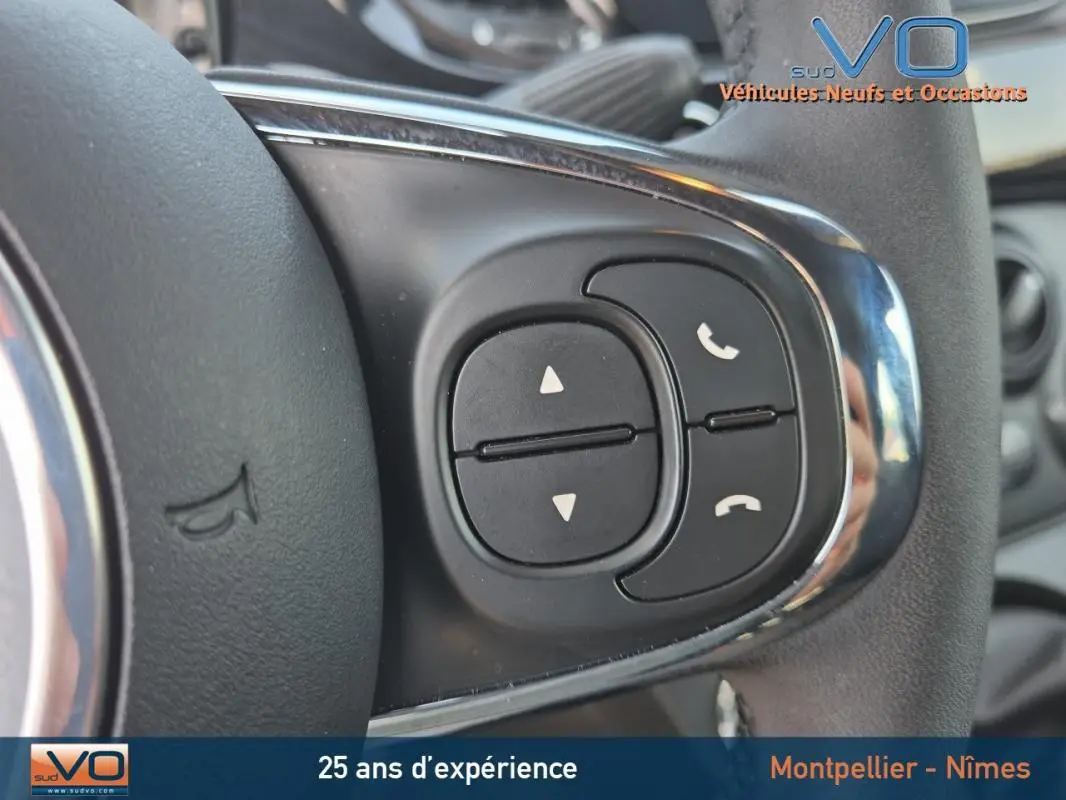 Gros plan sur les commandes de téléphonie au volant d'une FIAT 500C noire 2024 hybride essence.