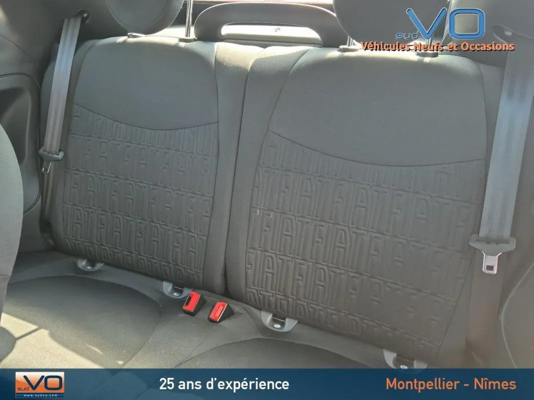 Gros plan sur les sièges arrière noirs de la Fiat 500C 2024, avec motif FIAT embossé et ceintures de sécurité visibles.