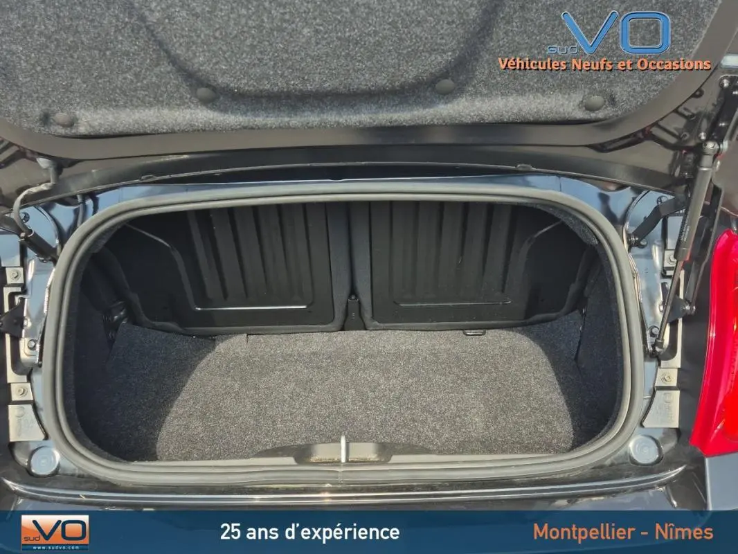 Coffre ouvert vu de dessus d'une FIAT 500C noire 2024 avec roue de secours visible sur le côté droit.