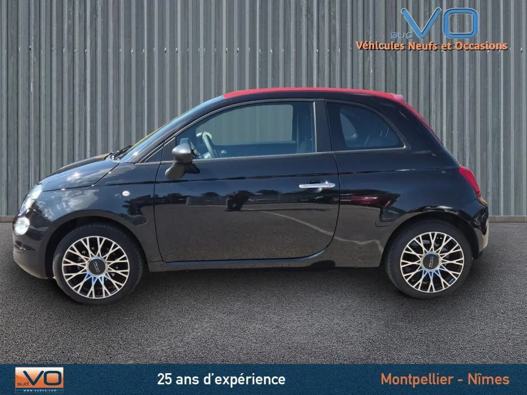 Profil côté gauche d'une FIAT 500C noire 2024 avec toit rouge et jantes multibranches, stationnée sur sol goudronné.