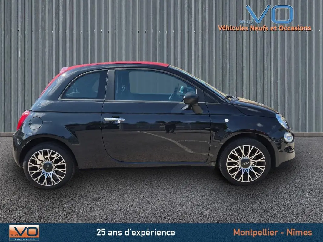 Profil côté gauche d'une FIAT 500C noire 2024 avec toit rouge et jantes alliage au design complexe, roue de secours visible.