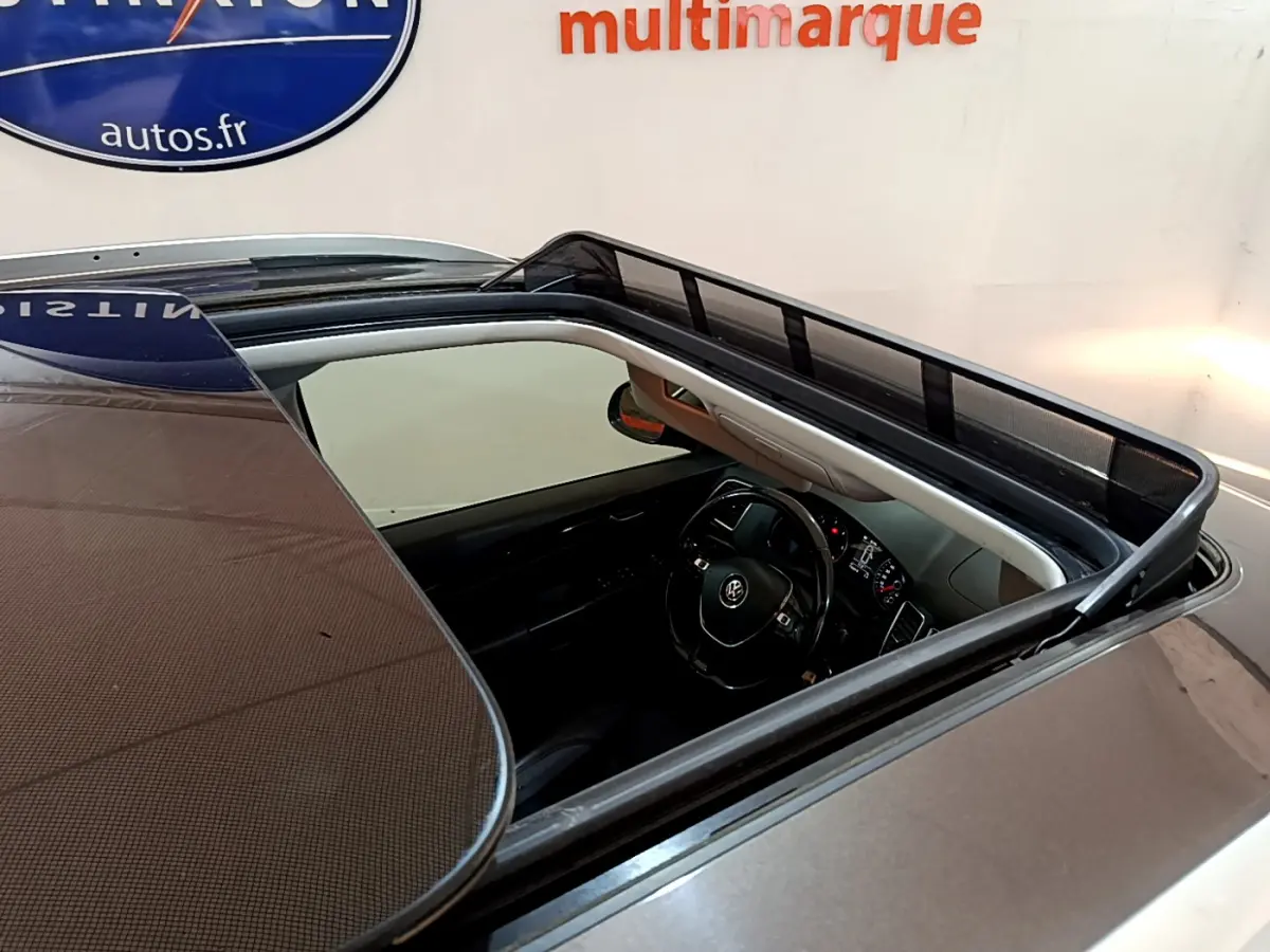 Vue plongeante sur le toit ouvrant ouvert d'un Volkswagen Sharan marron, dévoilant le volant et le tableau de bord intérieur.