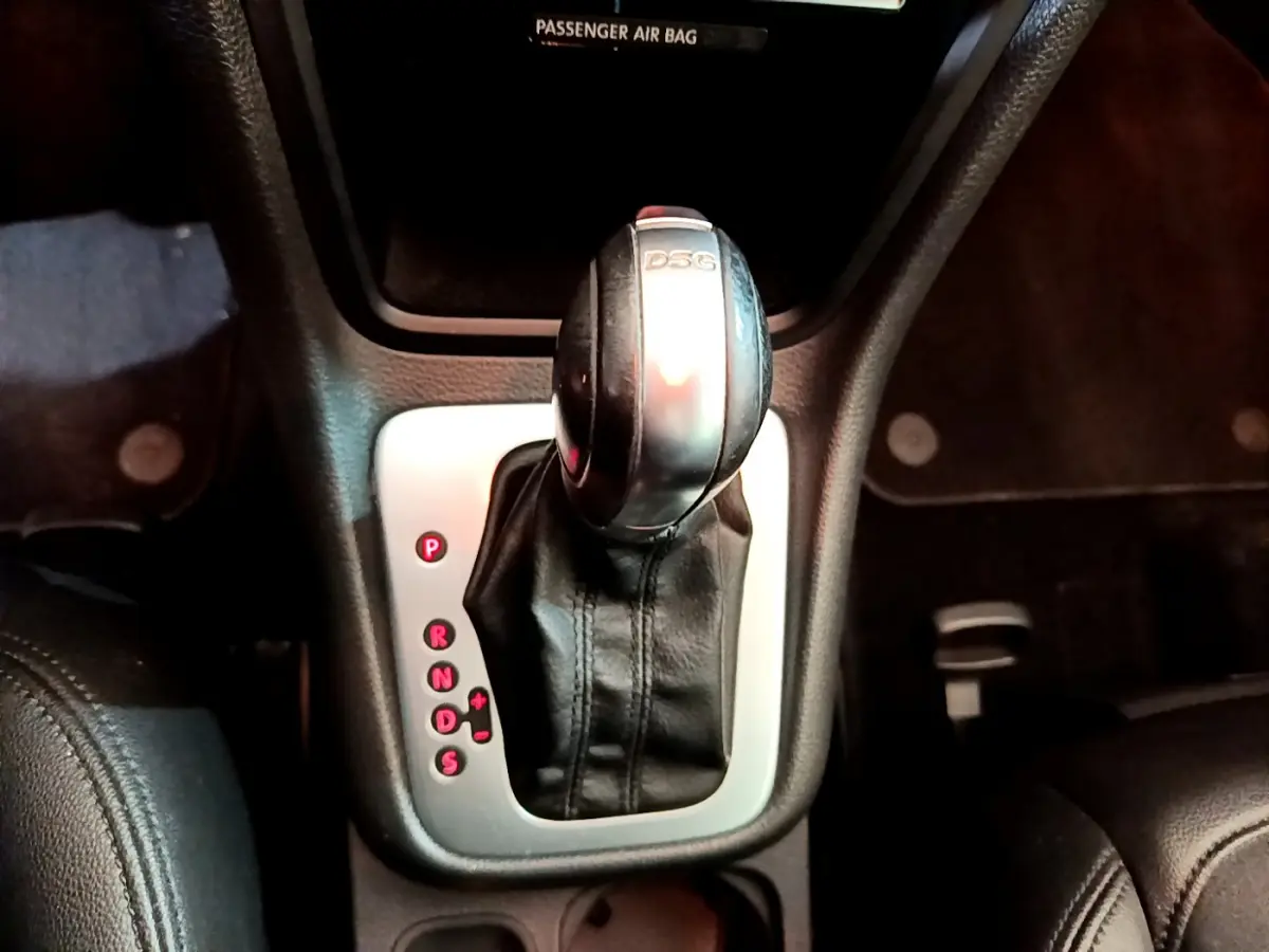 Le levier de vitesses DSG noir et argenté du Volkswagen Sharan 2017 vu de dessus dans un intérieur sombre.