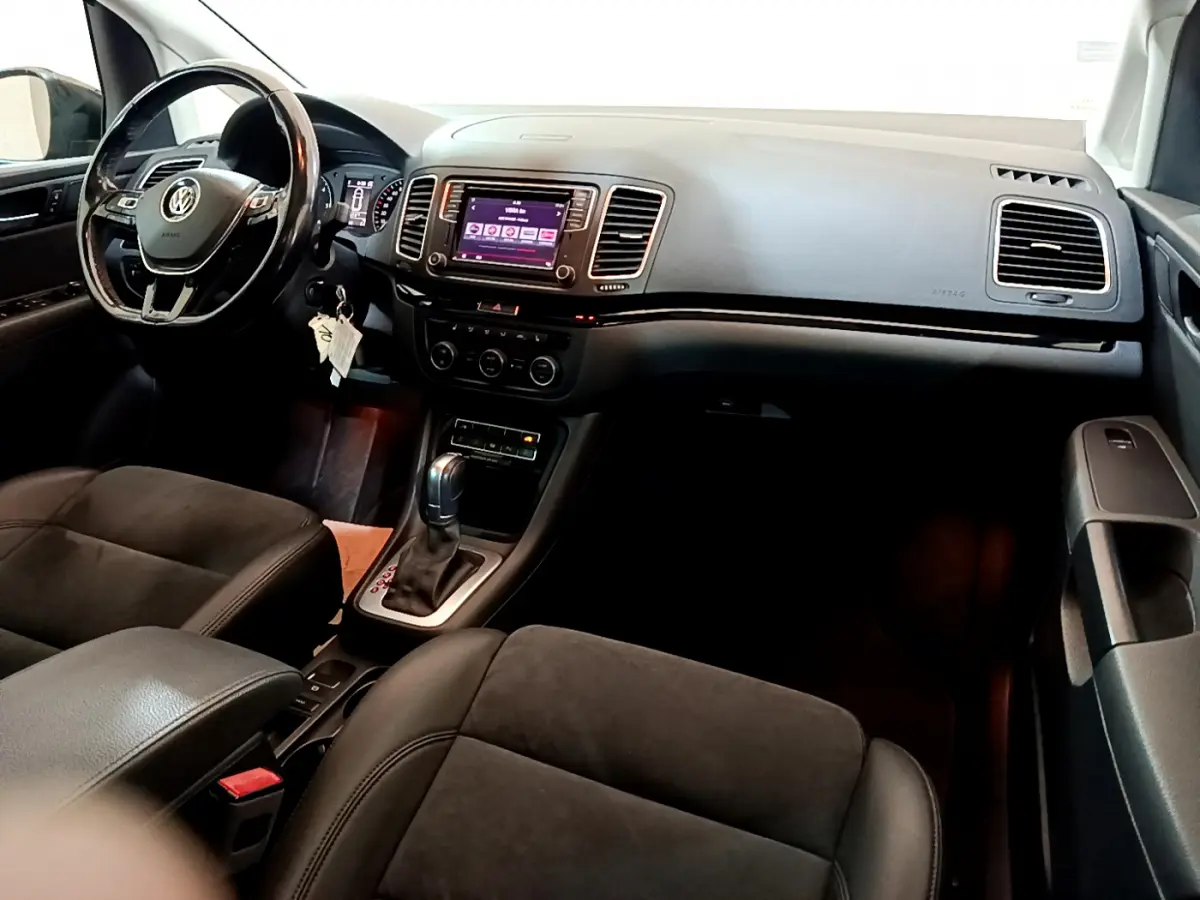 Intérieur noir du Volkswagen Sharan 2017 vu côté conducteur, avec tableau de bord et écran tactile central visible.