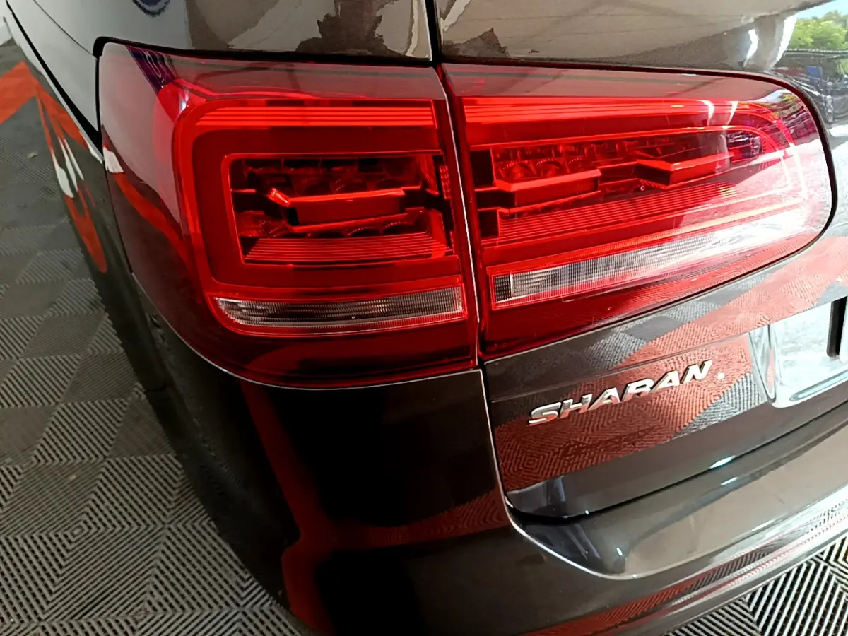 Gros plan sur le feu arrière gauche et le logo Sharan d'un Volkswagen Sharan marron 2017, vue arrière côté gauche.