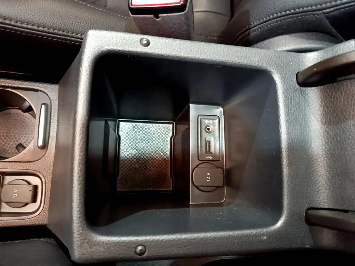 Vue rapprochée de la console centrale noire du Volkswagen Sharan 2017 avec prise 12V, USB et entrée audio auxiliaire.