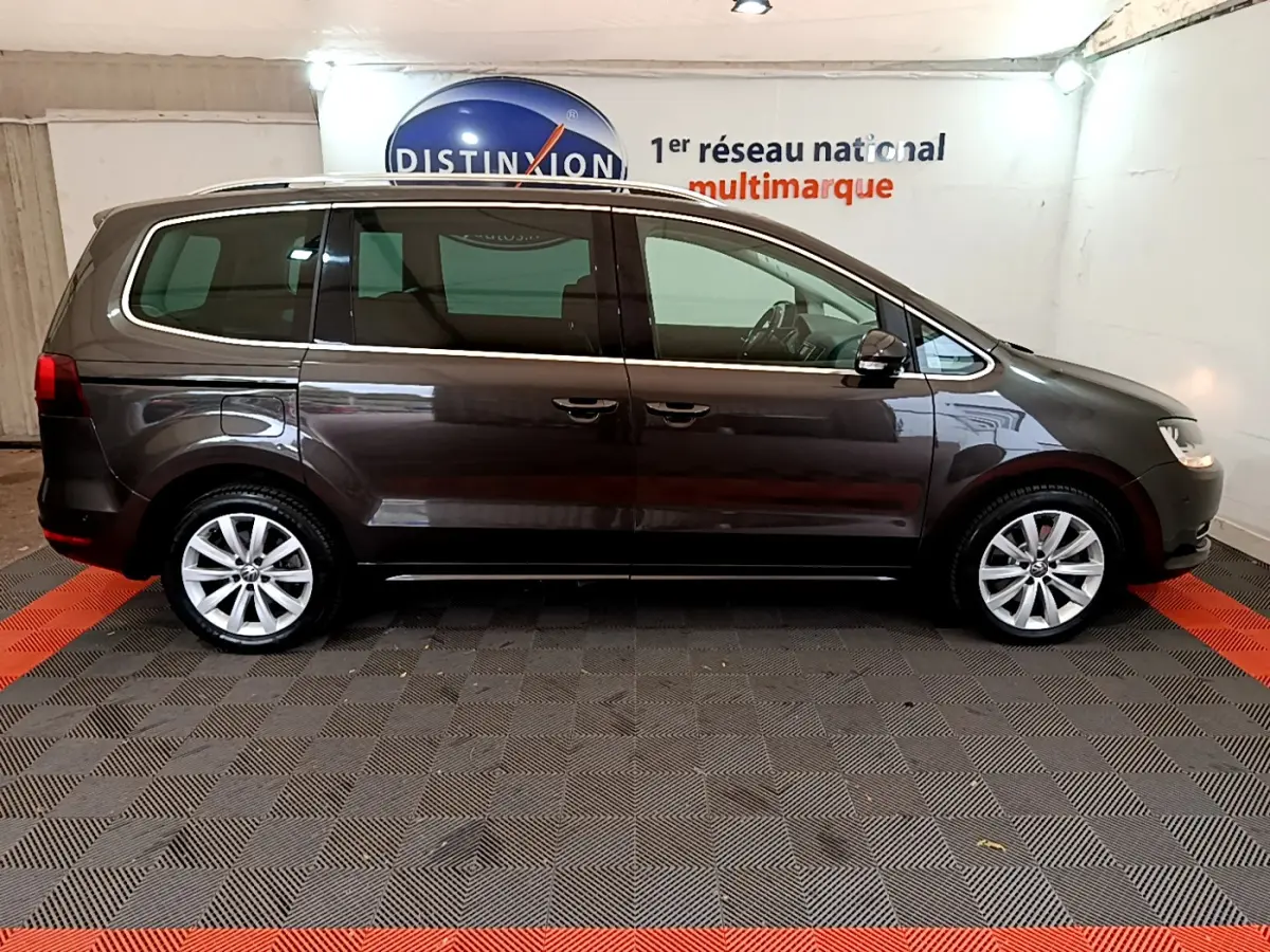 Profil droit d'un Volkswagen Sharan marron 2017 garé en intérieur sur sol carrelé noir et rouge.