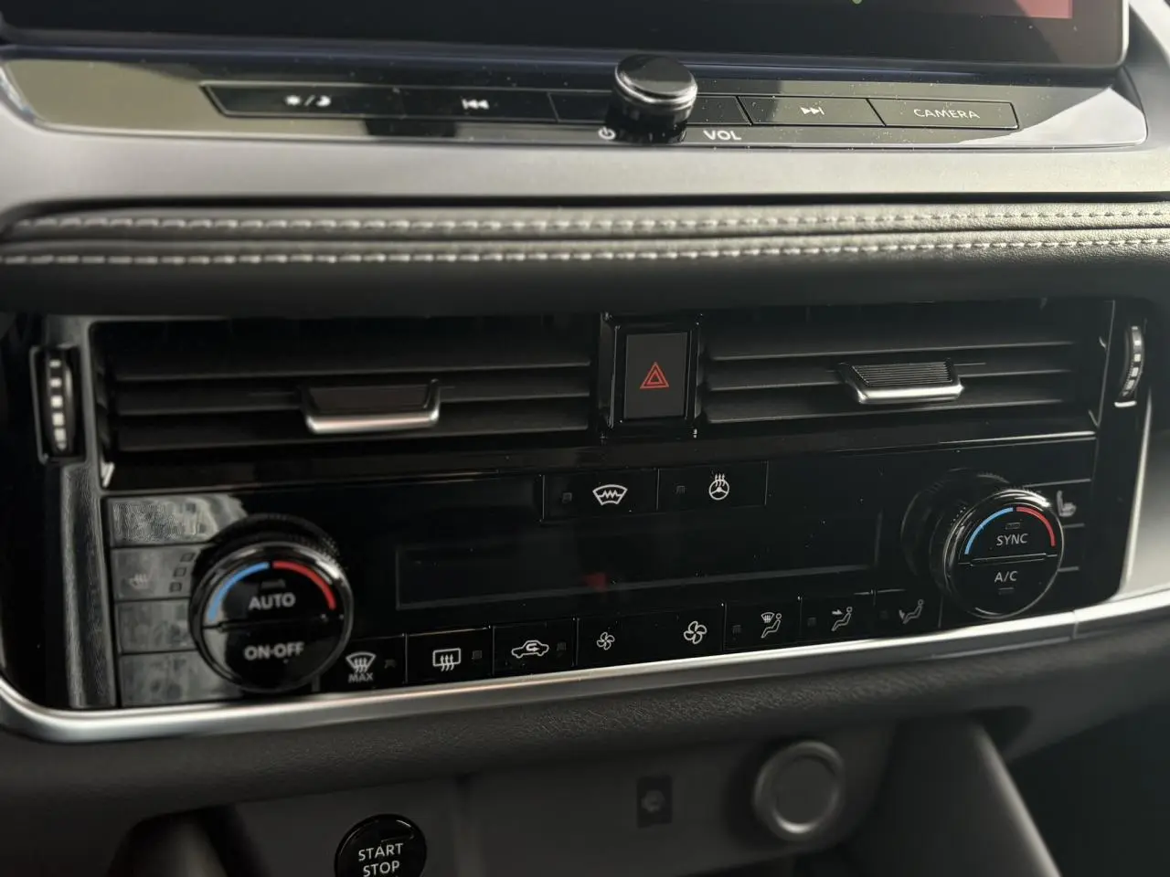 Gros plan sur la console centrale noire du Nissan Qashqai blanc nacré, montrant les commandes de climatisation automatique bi-zone.