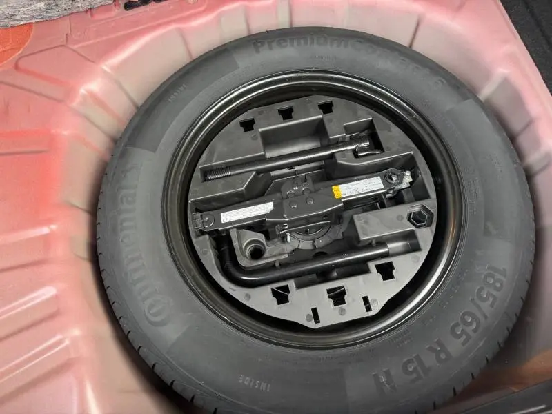 Vue en plongée sur la roue de secours et les outils de bord dans le coffre d'une Renault Clio Rouge Flamme 2025.