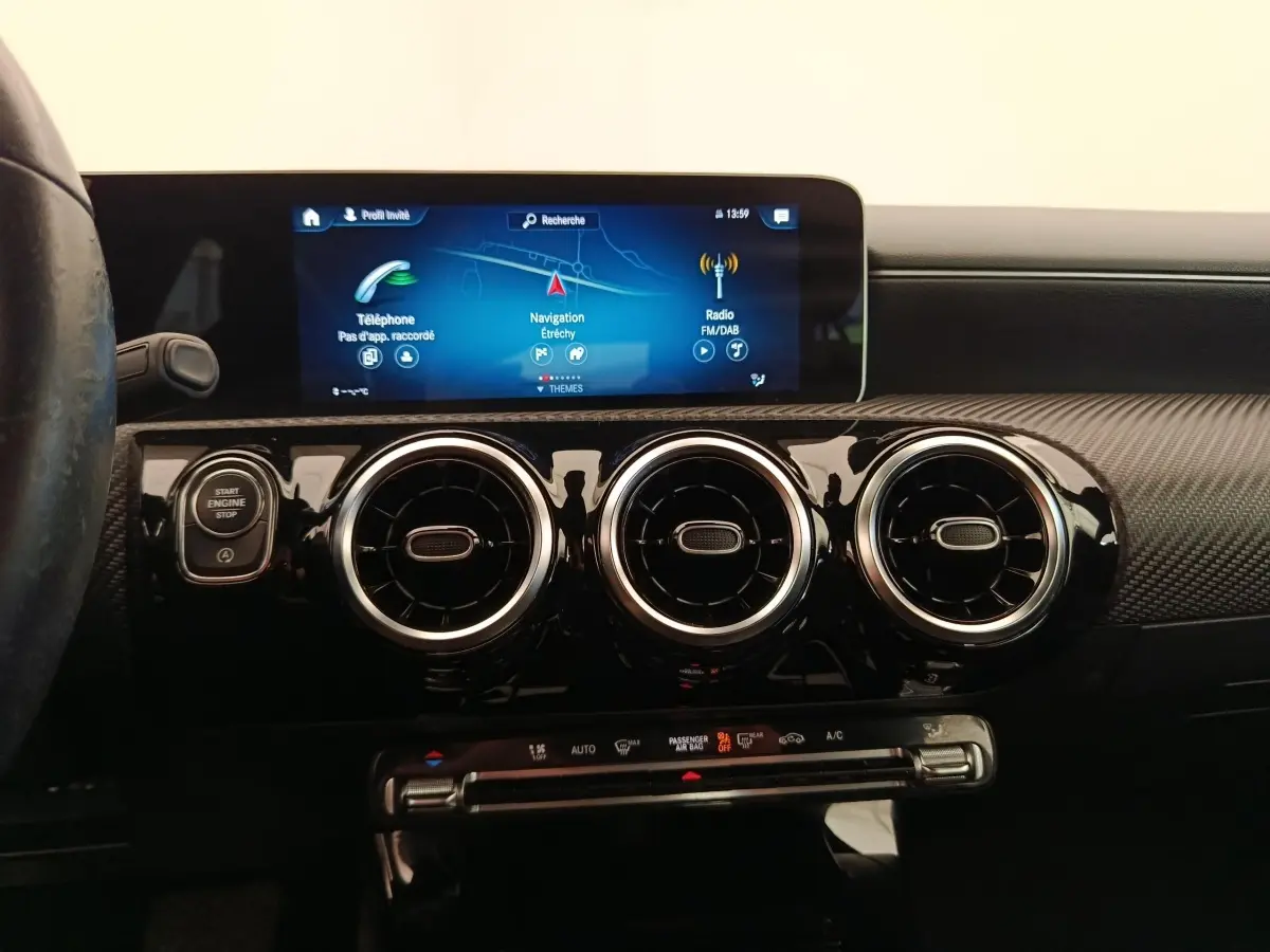 Vue intérieure centrée sur la console de la Mercedes Classe A 180 Business Line 2020, avec écran tactile et aérateurs ronds noirs.