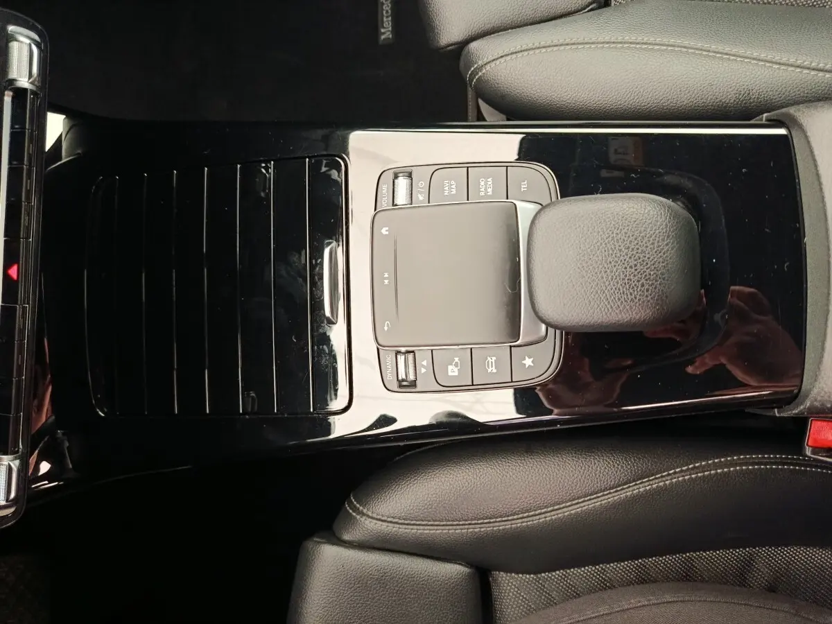 Vue plongeante sur la console centrale noire brillante de la Mercedes Classe A 180 Business Line avec levier de vitesses cuir.