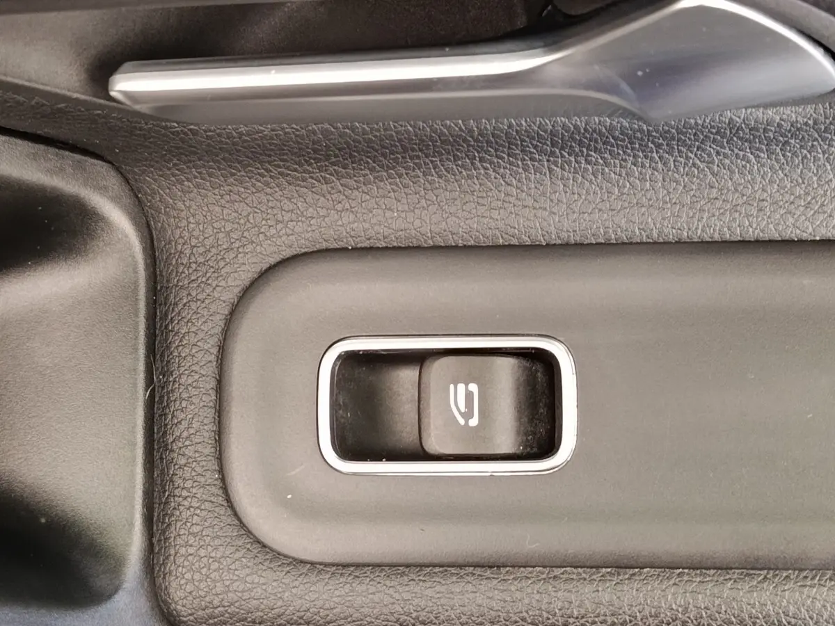 Gros plan sur le bouton de frein à main électrique entouré de plastique noir texturé dans une Mercedes Classe A 180 Business Line.