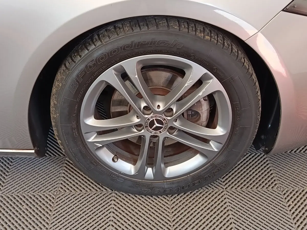 Gros plan sur la roue avant droite gris clair d'une Mercedes Classe A avec jante alliage à cinq branches doubles.