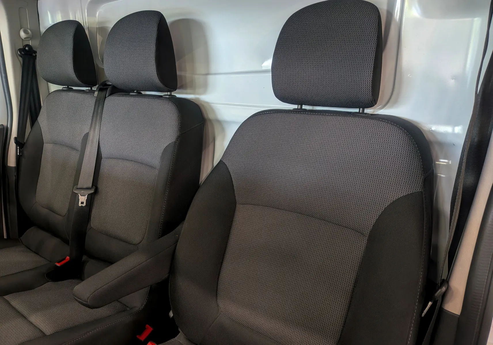 Vue rapprochée des sièges avant en tissu noir du Renault Trafic Fourgon 2024, avec ceinture de sécurité visible.