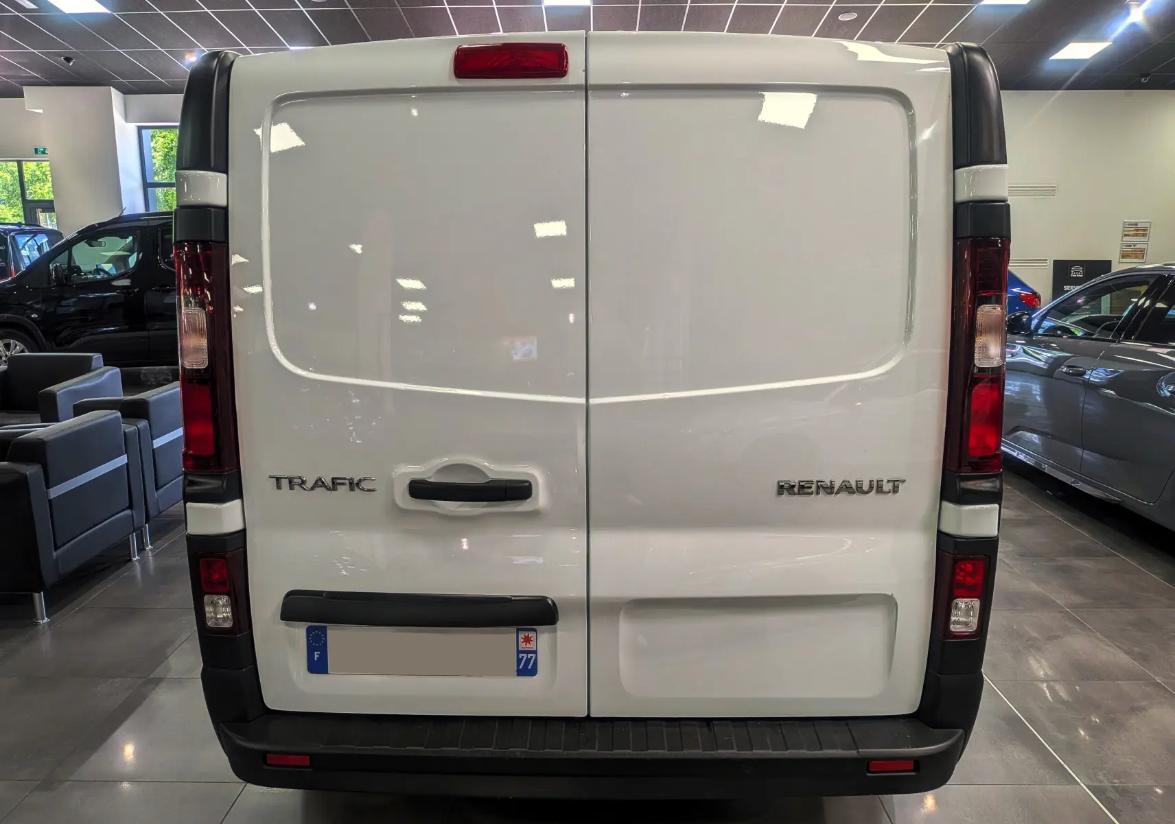 Vue arrière d’un Renault Trafic Fourgon blanc minéral 2024 avec portes battantes et feux verticaux rouges.