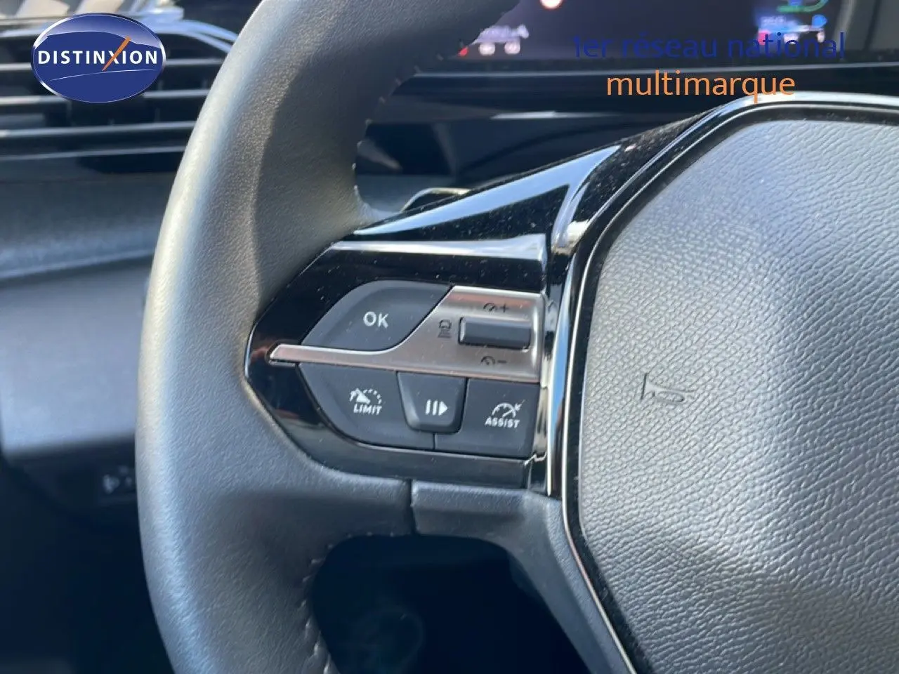 Gros plan sur le volant noir de la Peugeot 308 SW Hybrid 2025, montrant les commandes multifonctions côté gauche.