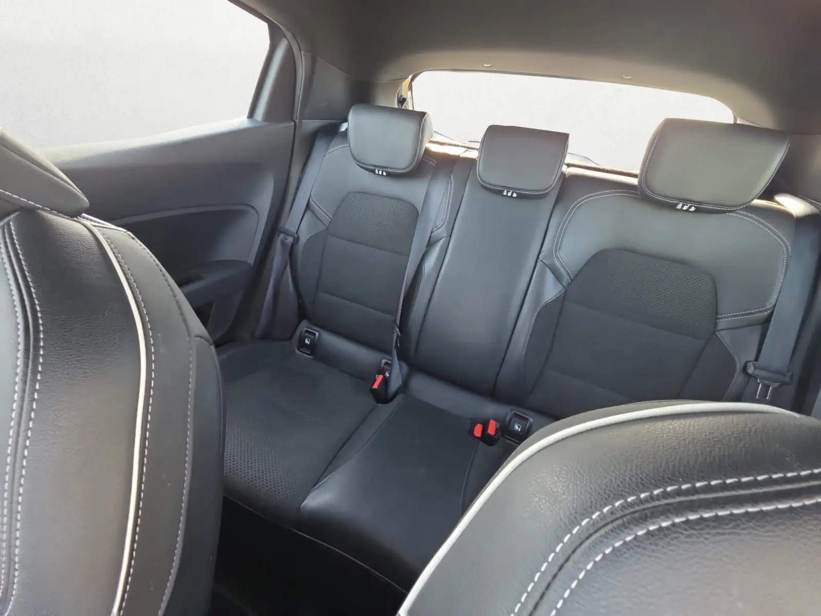 Vue intérieure arrière montrant les sièges en cuir noir avec surpiqûres blanches de la Renault Clio V TCE 90 Intens 2021.