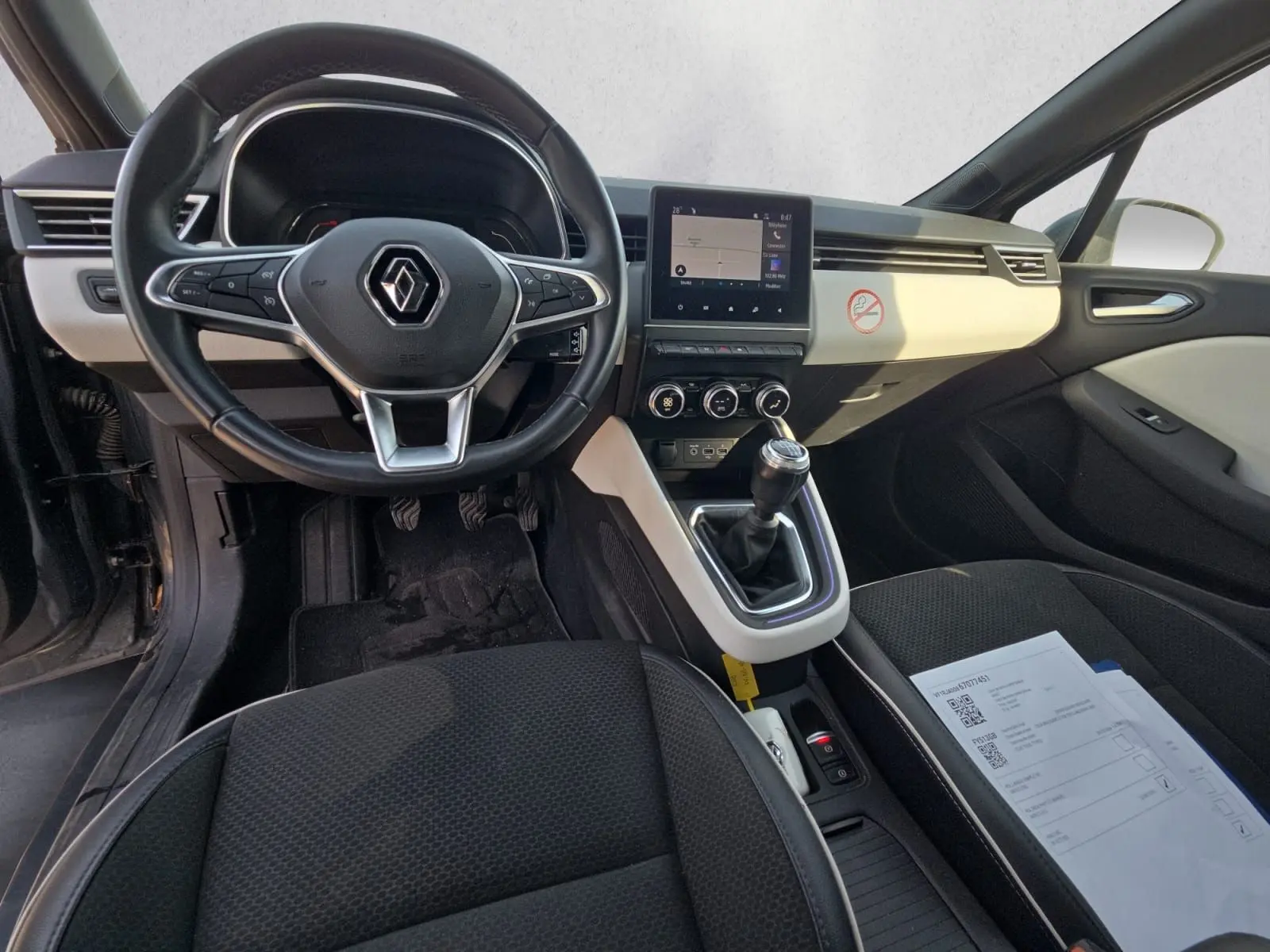 Vue intérieure avant de la Renault Clio V TCE 90 2021, volant multifonction, tableau de bord clair et levier de vitesse manuel.