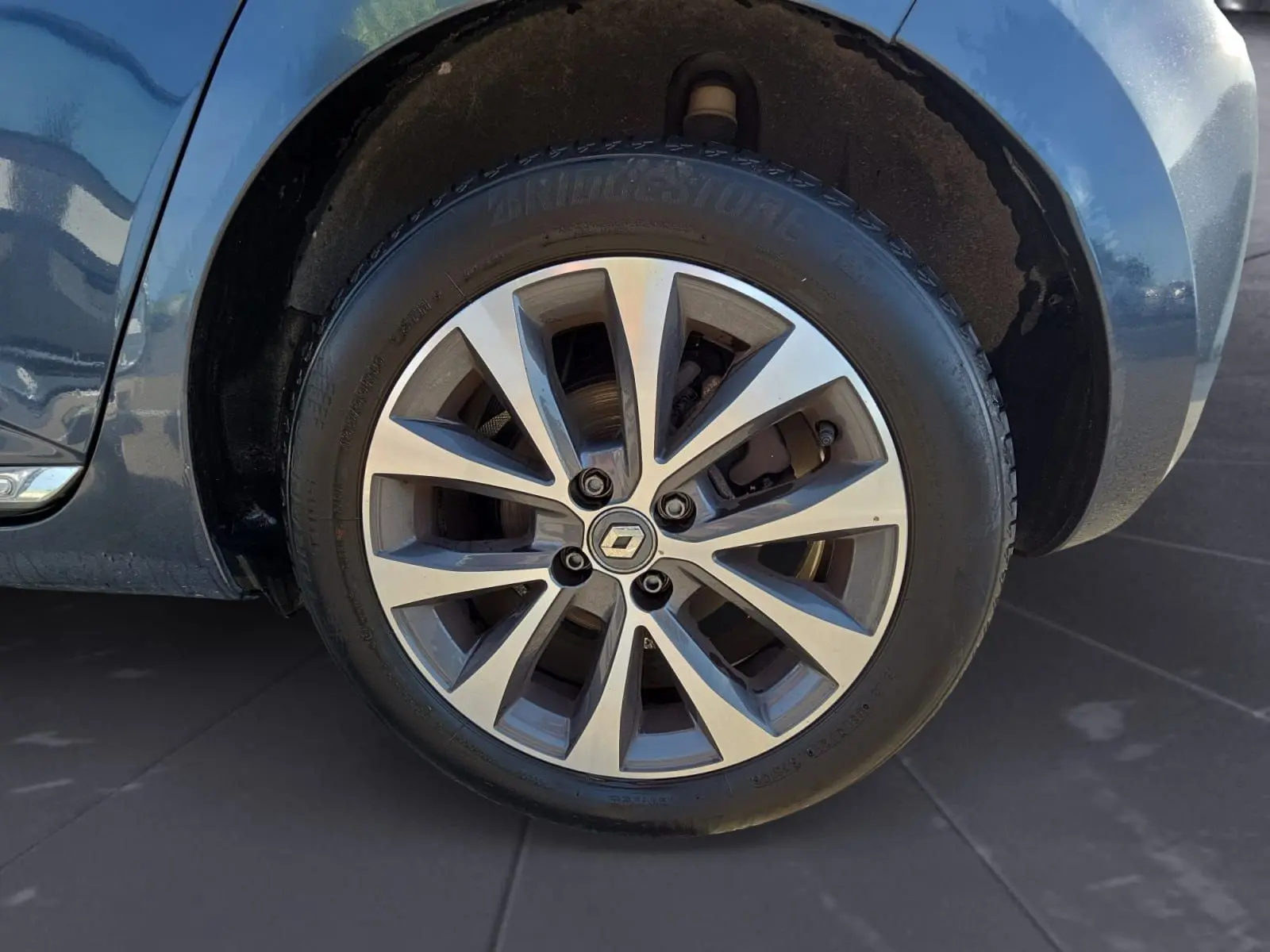 Gros plan sur la roue avant droite d’une Renault Clio V gris foncé métal, jante alliage à plusieurs branches.
