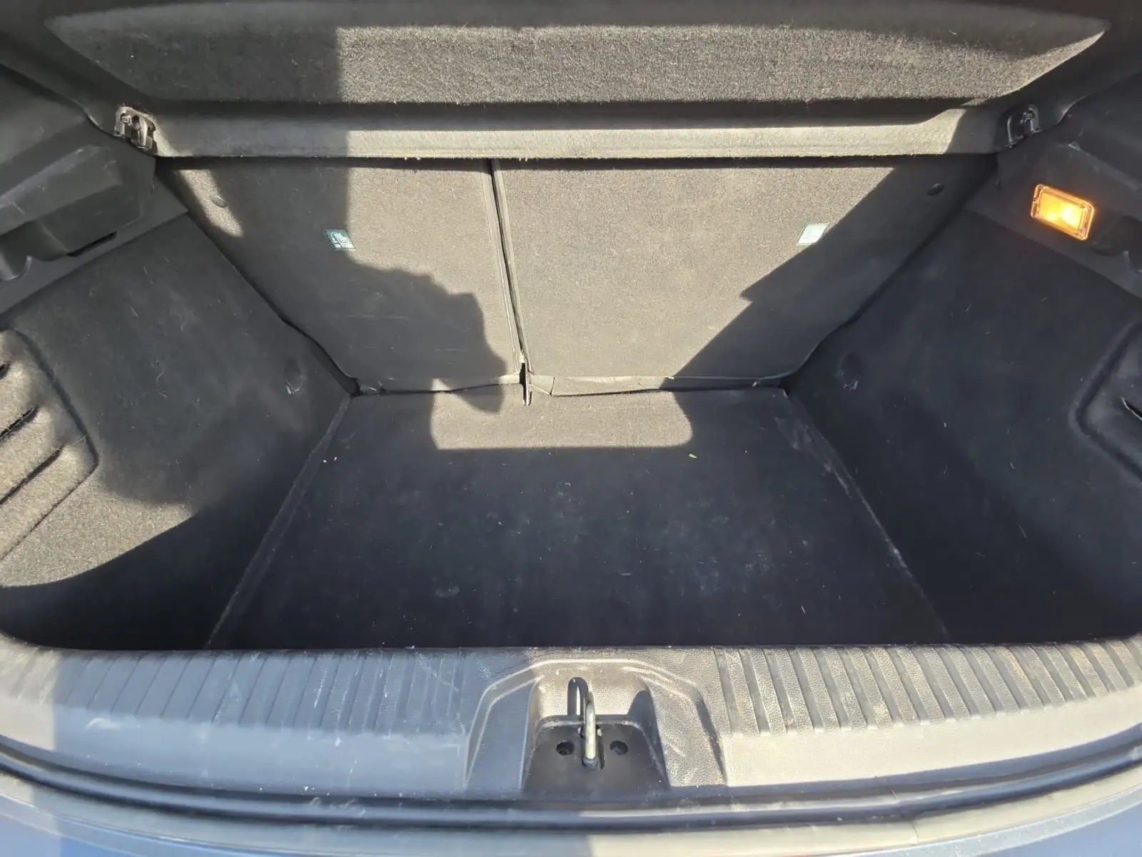 Coffre ouvert vu de face d’une Renault Clio V gris foncé métal, montrant un espace de chargement propre et éclairé.