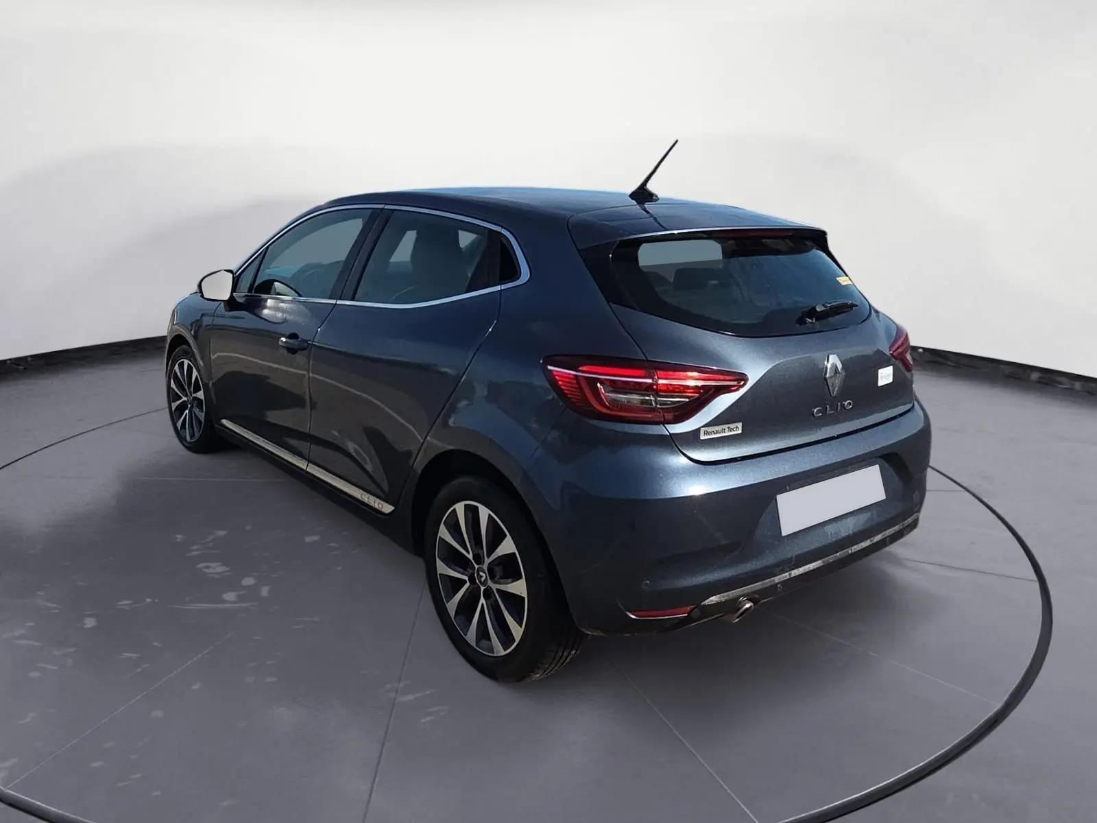 Renault Clio V TCE 90 2021 gris foncé métal vue 3/4 arrière droit avec jantes alliage et feux LED allumés.