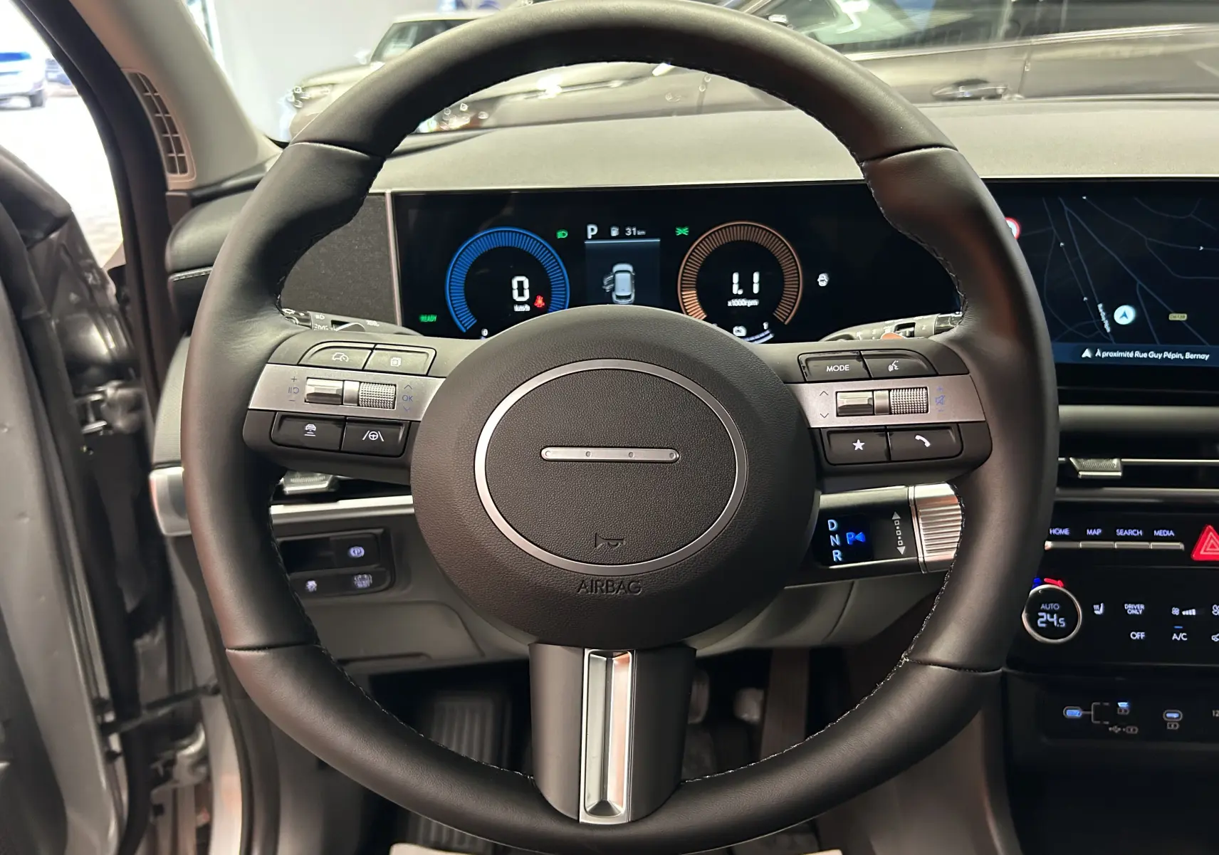 Vue rapprochée du volant noir et du tableau de bord numérique du Hyundai Tucson 2025 hybride en intérieur.