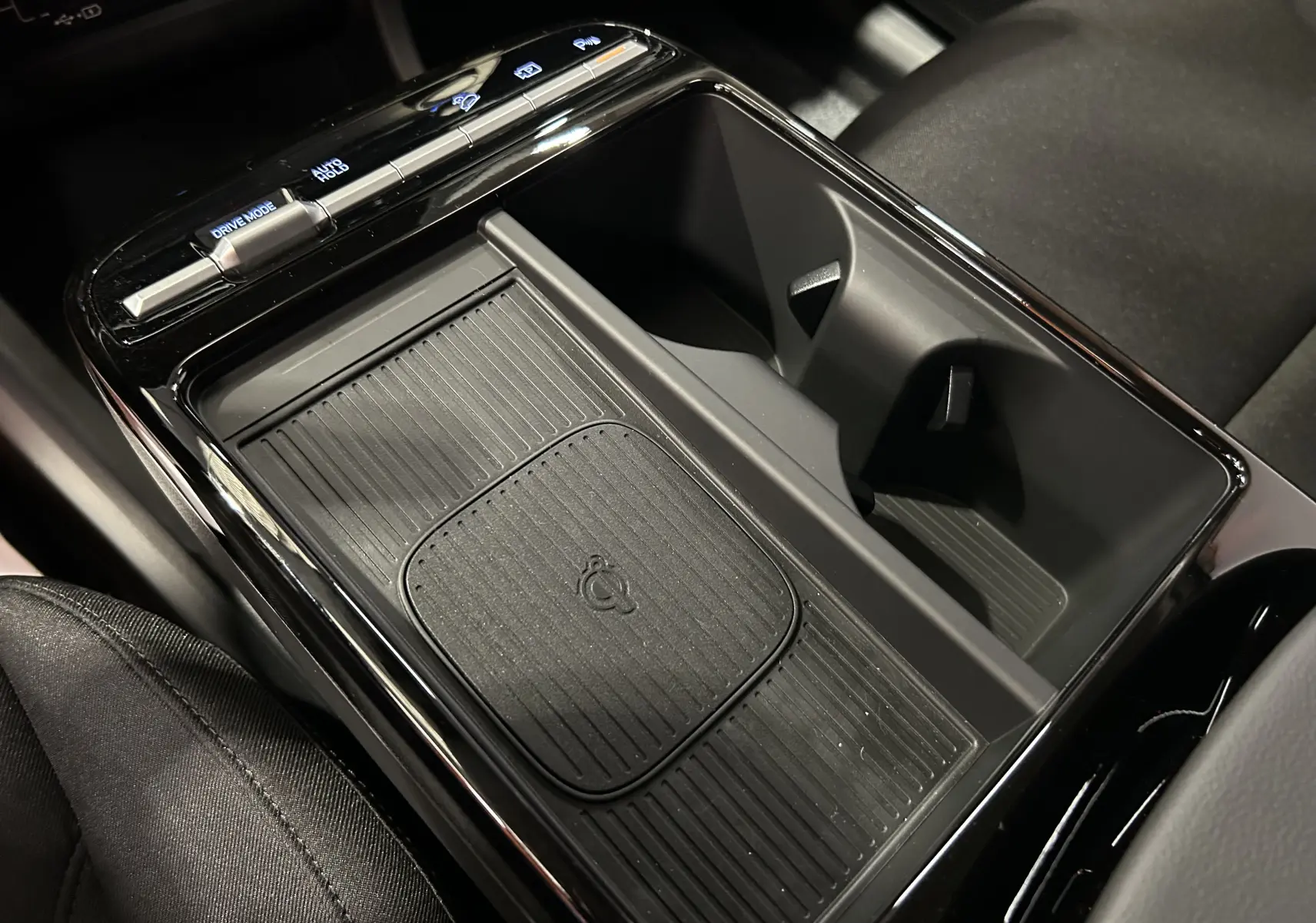 Gros plan sur la console centrale noire du Hyundai Tucson 2025 avec zone de recharge sans fil et commandes tactiles.