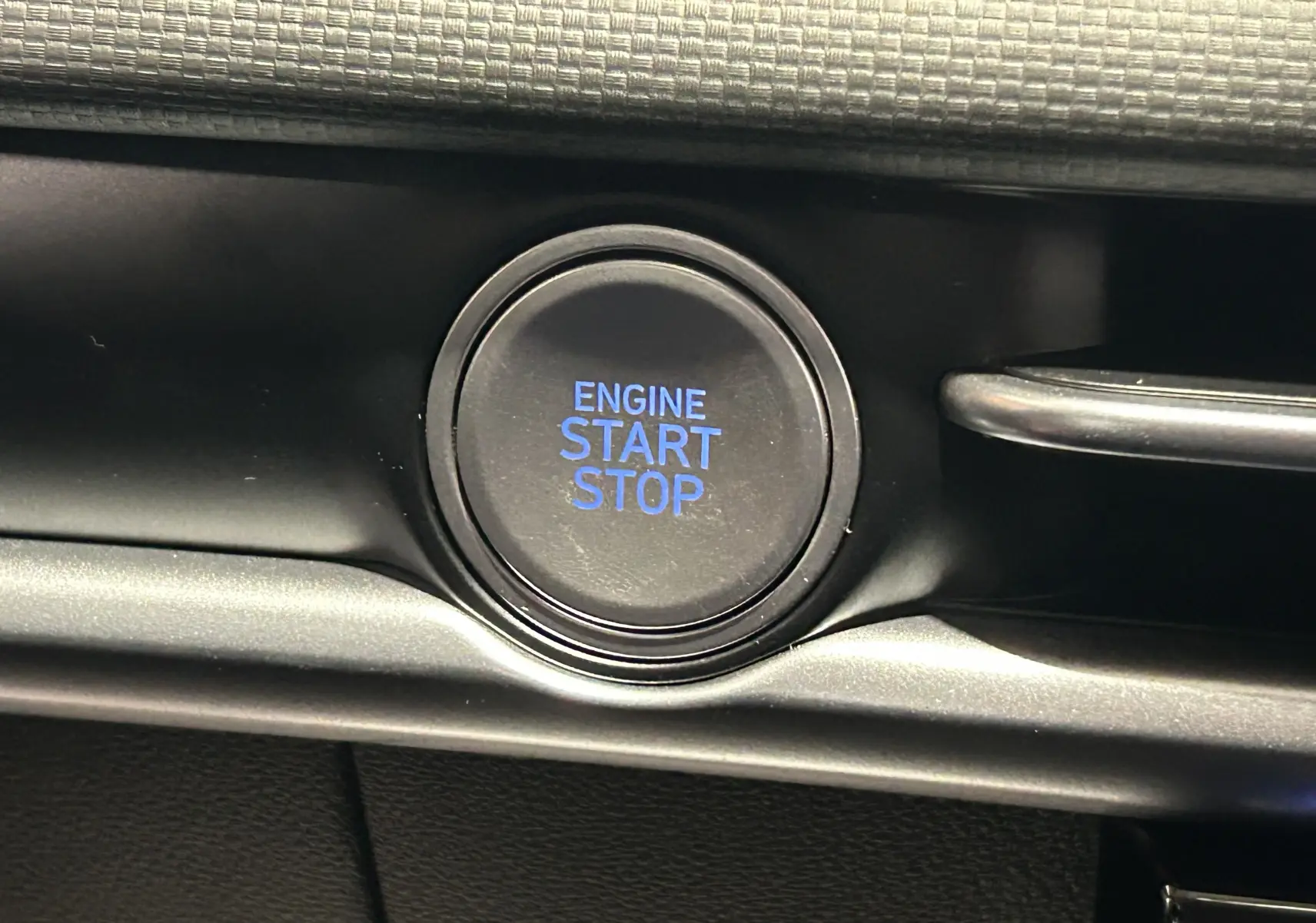 Bouton noir d'allumage moteur avec inscription bleue "ENGINE START STOP" dans l'habitacle du Hyundai Tucson 2025.