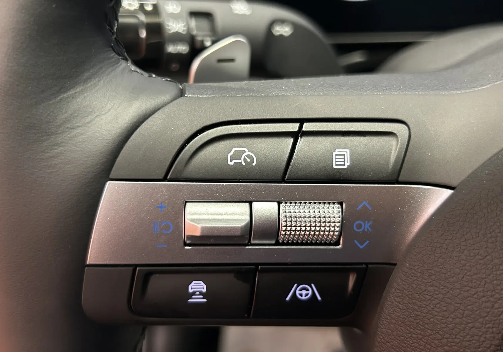 Gros plan sur les commandes du volant du Hyundai Tucson 2025, boutons noirs et argentés avec symboles de régulateur et assistance.