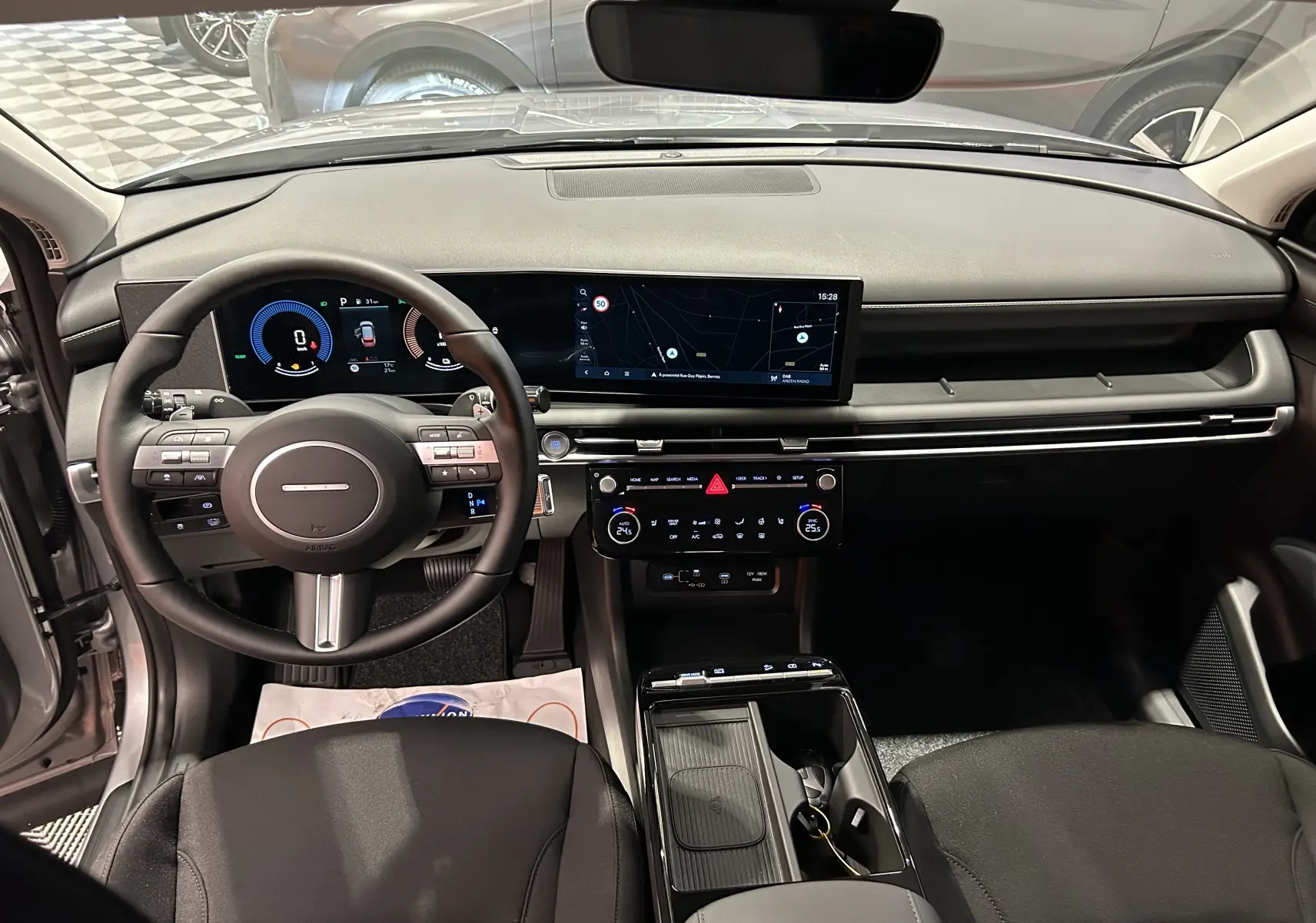Intérieur du Hyundai Tucson 2025 en Shimmering Silver, vue frontale du tableau de bord avec écran large et volant multifonction.
